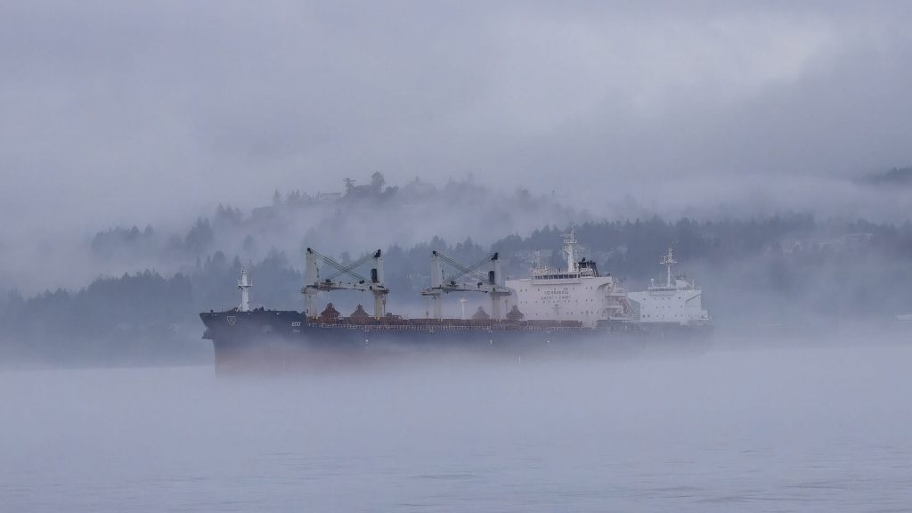 foggy cargo ship going through weather disruptions to import goods freight